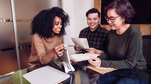 Three people sitting around a table looking at a contract