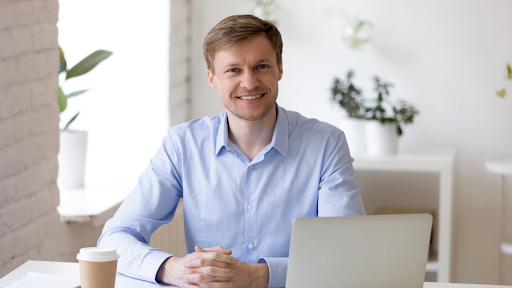 A man smiling behind a desk