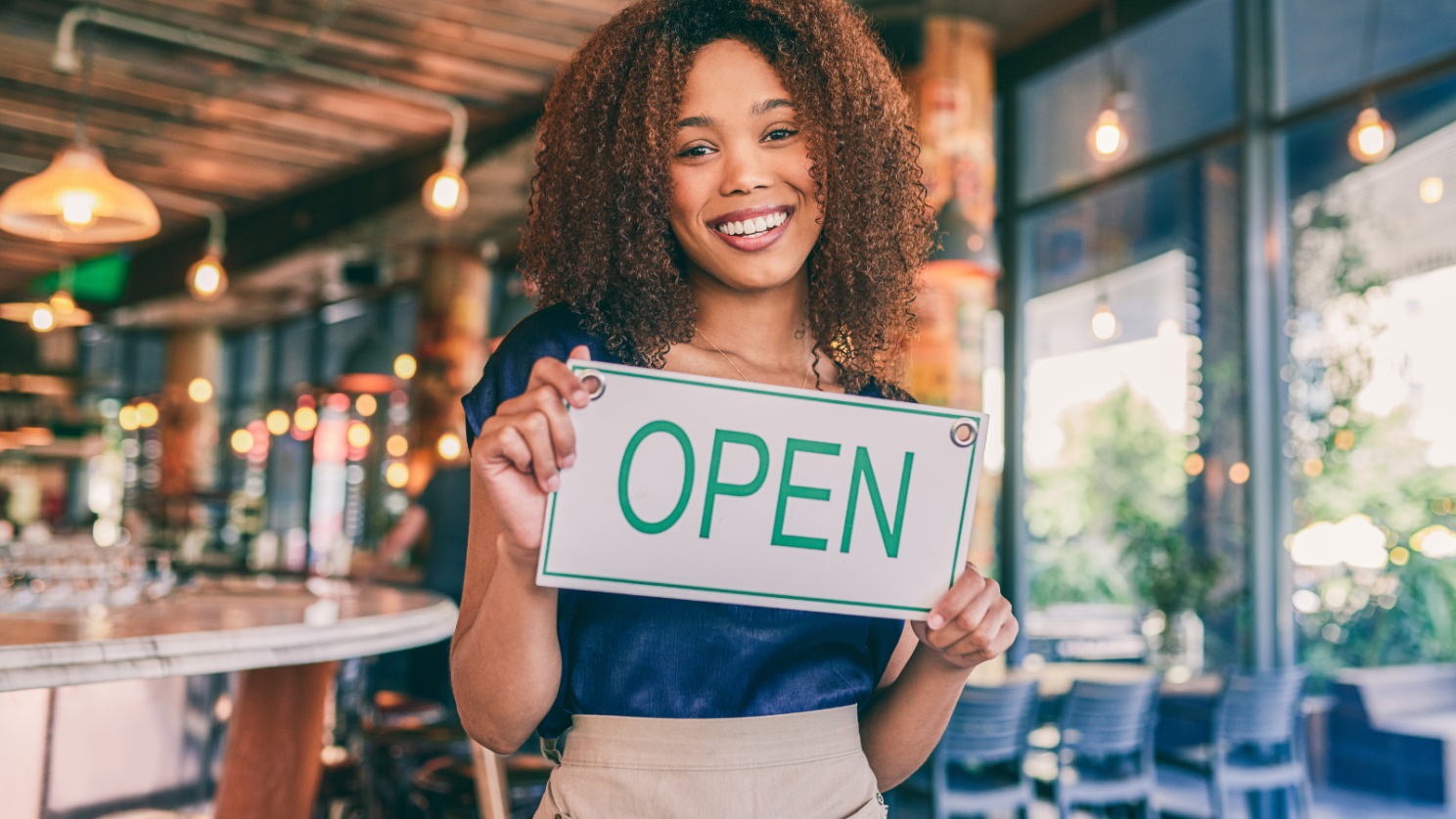 A woman holding an open sign